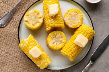 Gri arka planda tereyağlı haşlanmış mısır koçanı tabağı