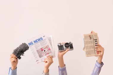 Gazeteli kadın eller, fotoğraf makinesi ve arka planda mikrofon.