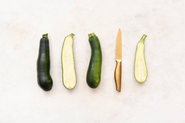 Beyaz zemin üzerinde bıçak olan taze yeşil kabak.