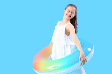 Yüzünde şişirilebilir yüzük ve mavi arka planda güneş kremi olan küçük kız.