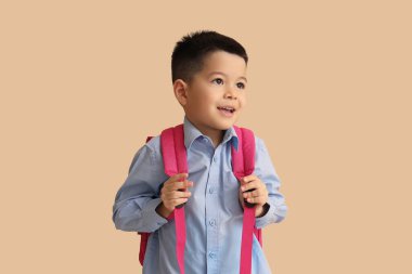 Bej arka planda sırt çantası olan küçük bir okul çocuğu.