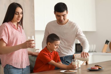 Ailesiyle birlikte mutfakta süt içen küçük bir çocuk.