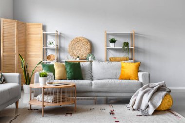 Rahat gri kanepe, kahve masası ve oturma odasının iç tarafında yumuşak battaniyeli puf.