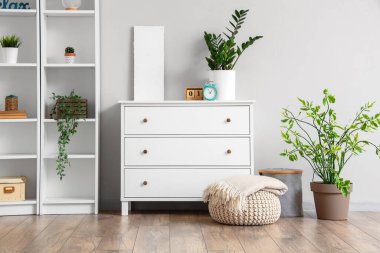 Aydınlık oturma odasının iç tarafında yumuşak battaniyeli çekmeceler ve puf.