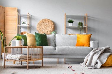 Rahat gri kanepe, kahve masası ve oturma odasının iç tarafında yumuşak battaniyeli puf.