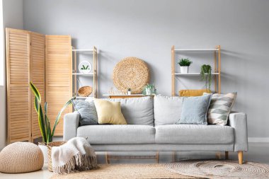 Işıl ışıl oturma odasının içinde yumuşak battaniyeli rahat gri kanepe ve sepet.