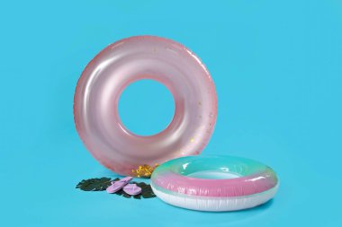 Mavi arka planda parmak arası terlikleri ve avuç içi yaprakları olan şişme halkalar.