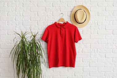 Beyaz tuğla duvarda asılı şık kırmızı tişört ve şapka