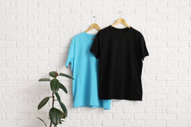 Beyaz tuğla duvarda asılı şık tişörtler
