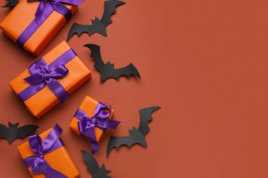 Kahverengi arka planda Cadılar Bayramı için hediye kutuları ve kağıt yarasalarla kompozisyon