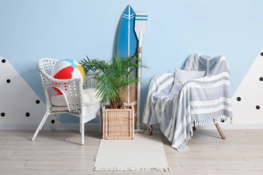 Oturma odasının içinde koltuklar, sörf tahtası ve plaj topu var.