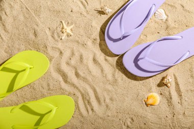 Kumlu arka planda renkli parmak arası terliklerden oluşan çerçeve