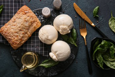 Lezzetli Burrata peyniri, fesleğenli ve koyu arkaplanda ekmek.