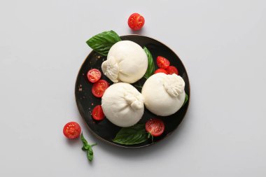 Beyaz arka planda fesleğenli ve domatesli bir tabak lezzetli Burrata peyniri.