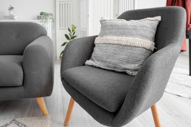 Aydınlık oturma odasının içindeki şık gri koltuk.