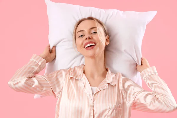 穿着睡衣 头枕粉色背景的年轻女子 — 图库照片