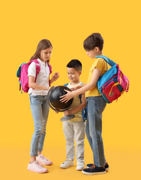 黄色の背景に地球を持つ小さな生徒 — ストック写真