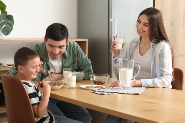 Happy family drinking milk with cookies at breakfast in kitchen