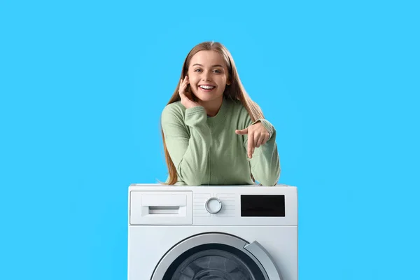 여자가 세탁기에 기대고 파란색 배경에 그것을 — 스톡 사진