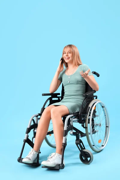 Молодая Женщина Инвалидной Коляске Разговаривает Мобильному Телефону Синем Фоне — стоковое фото