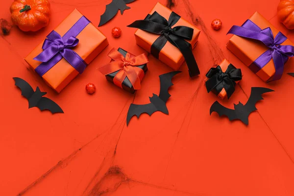 Composition with gift boxes, pumpkins and paper bats for Halloween on orange background