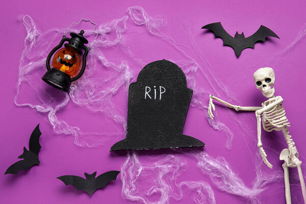Composition with lantern, skeleton, grave and paper bats for Halloween on purple background