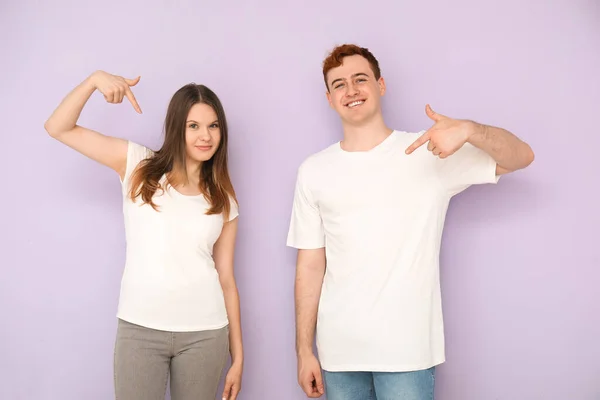 Casal Jovem Apontando Para Suas Camisetas Brancas Fundo Lilás — Fotografia de Stock