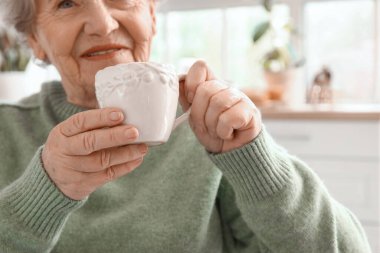 Üst düzey kadın mutfakta çay içiyor, yakın plan.