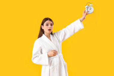 Sarı arka planda alarmlı genç bir kadın şok oldu.