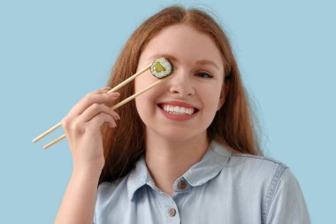 Mavi arka planda lezzetli suşisi olan genç bir kadın, yakın plan.