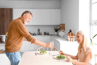 Olgun bir çift mutfakta yemek yiyor.