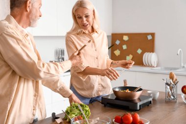 Mutfakta baharat pişiren olgun bir çift.