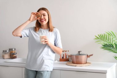 Mutfakta bir bardak süt ve kurabiyeyle genç bir kadın.