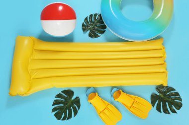 Mavi arka planda plaj aksesuarları olan şişme yatak ve yüzük.