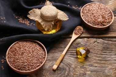 Keten yağı kavanozları ve tahtadan arka planda tohumları olan kaseler.