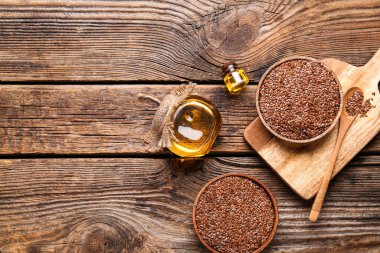 Keten yağı kavanozları ve tahtadan arka planda tohumları olan kaseler.