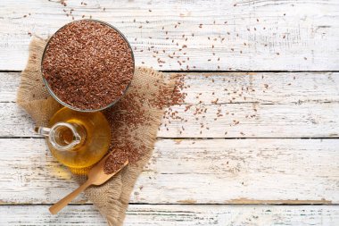 Beyaz ahşap arka planda tohumlu keten yağı ve kase.