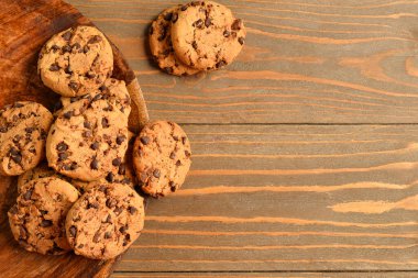 Tahta arka planda çikolata parçalı lezzetli kurabiyeler.