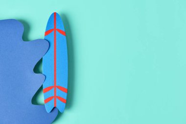 Kağıt dalga ve turkuaz arka planda mini sörf tahtası olan yaratıcı kompozisyon