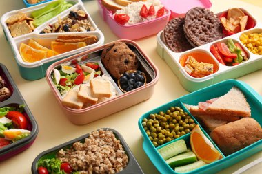 Sönük sarı arka planda farklı lezzetli yemekleri olan bir sürü beslenme çantası.