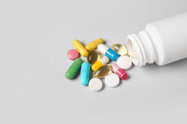 Gri arka planda farklı dağılmış haplarla dolu kavanoz.