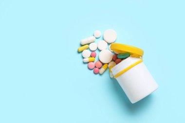 Mavi arka planda farklı dağınık haplarla dolu kavanoz.