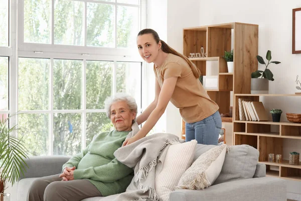 stock image Young woman covering her grandmother with plaid at home