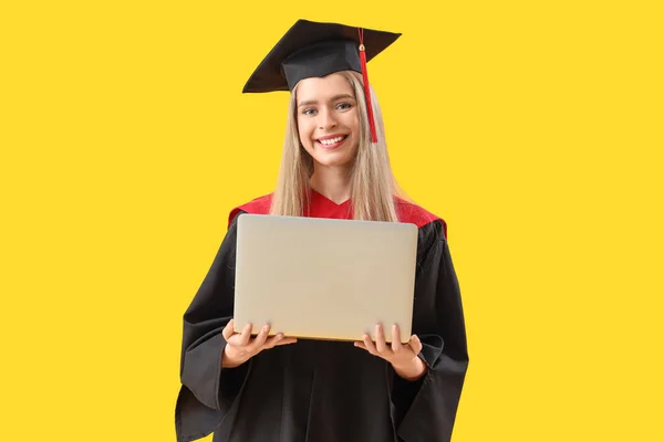 黄色の背景にラップトップを持つ女性の大学院生 — ストック写真