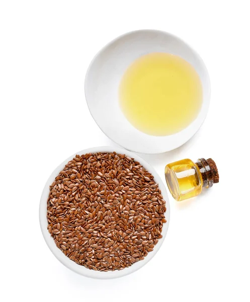 Beyaz arka planda tohumları olan keten yağı ve kase.