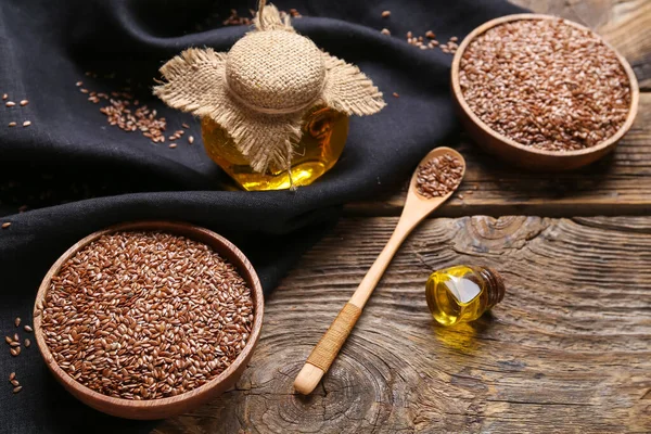 Keten yağı kavanozları ve tahtadan arka planda tohumları olan kaseler.