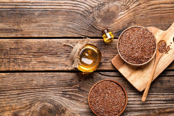 Keten yağı kavanozları ve tahtadan arka planda tohumları olan kaseler.