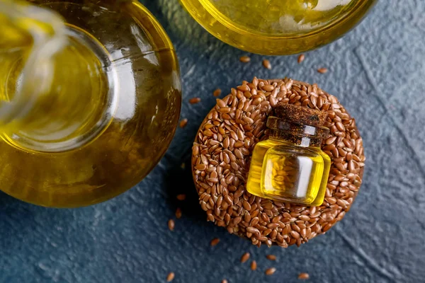 Bir kavanoz keten yağı ve mavi arka planda tohumlar.