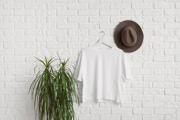 Beyaz duvarda asılı şık bir tişört ve şapka