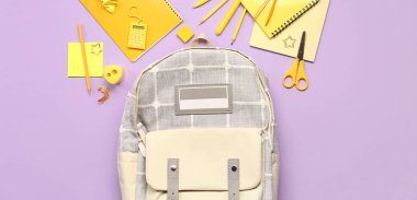 Okul çantası ve eflatun arka planda farklı kırtasiye malzemesi, üst görünüm